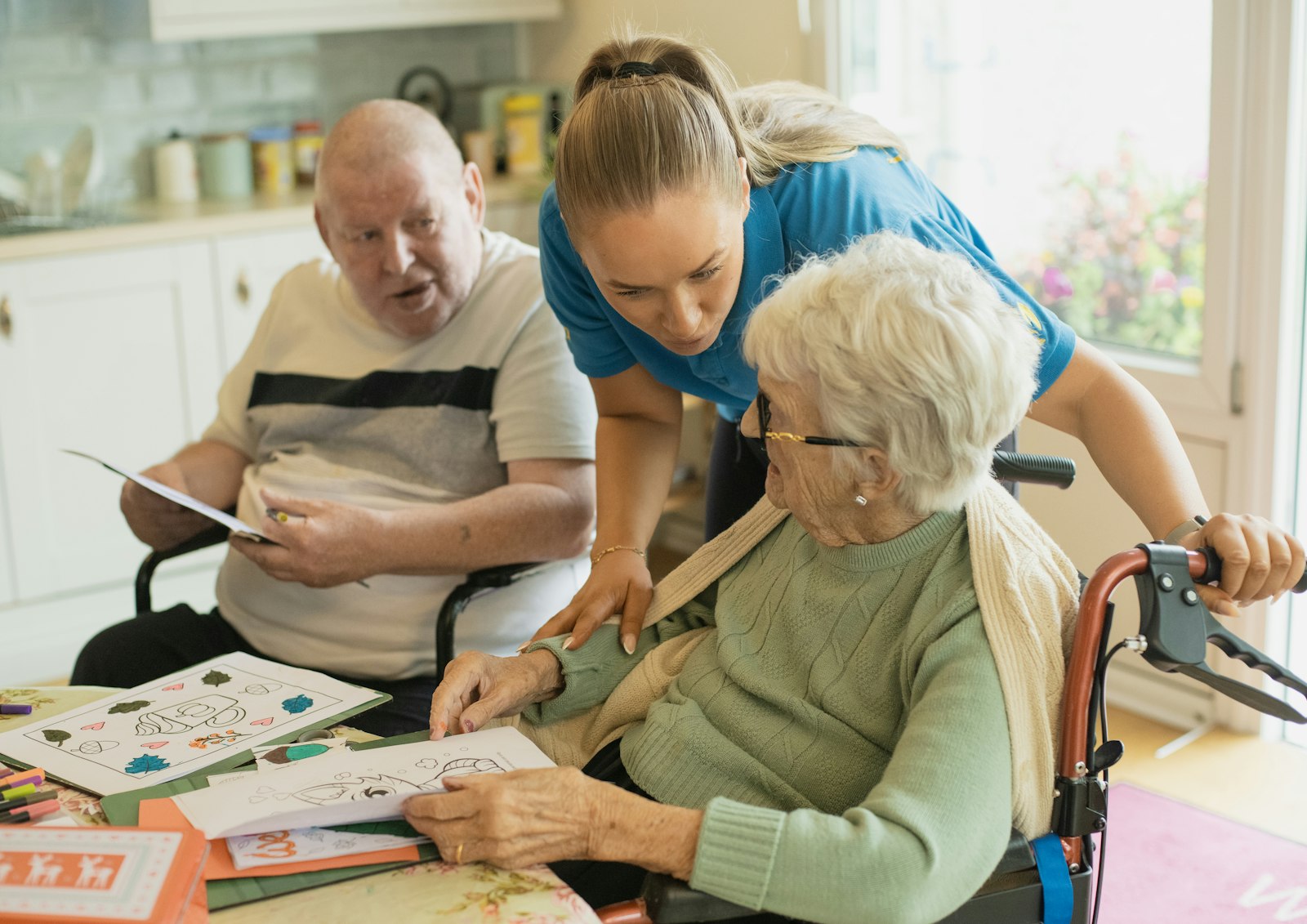 A caregiver doing a memory-focused coloring activity with an elderly couple