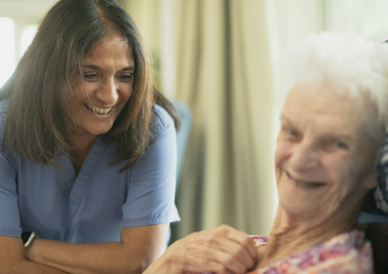 A smiling caregiver spending time with a senior client at home
